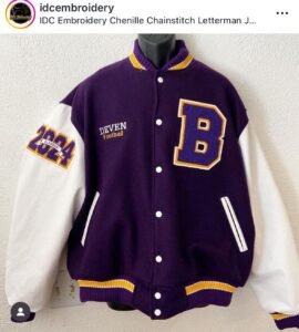 Custom purple and white letterman jacket with a large embroidered “B” and varsity patches.
