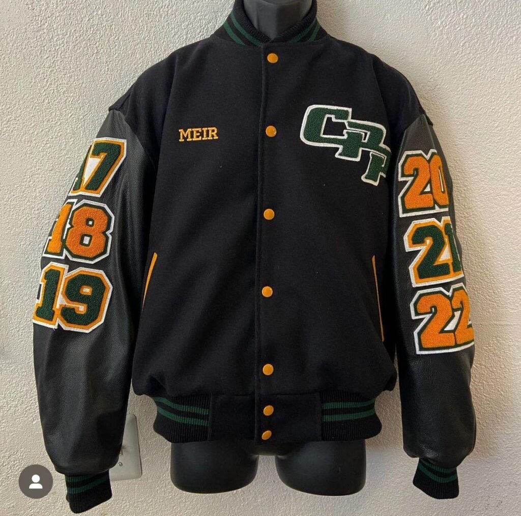 Black varsity jacket with orange and gold embroidered number patches