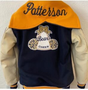Custom navy blue and cream letterman jacket with an orange embroidered “Patterson” cap and school-style patches.