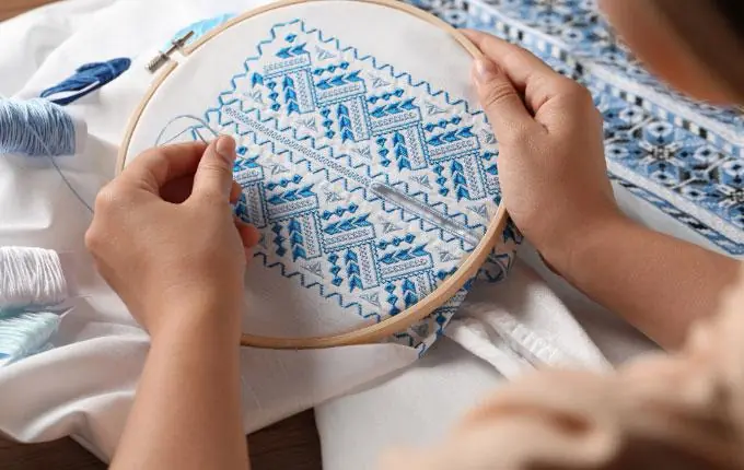 Detailed embroidery stitching on fabric in an embroidery hoop, illustrating intricate customization work.