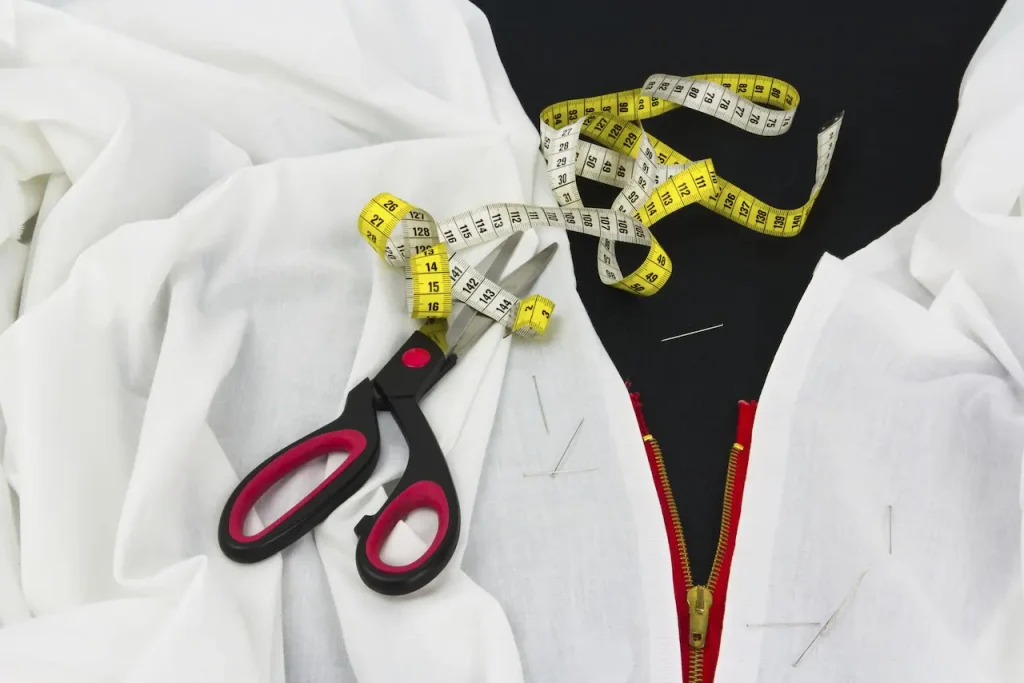Flexible measuring tape arranged with sewing materials for checking letterman jacket sizing measurements.