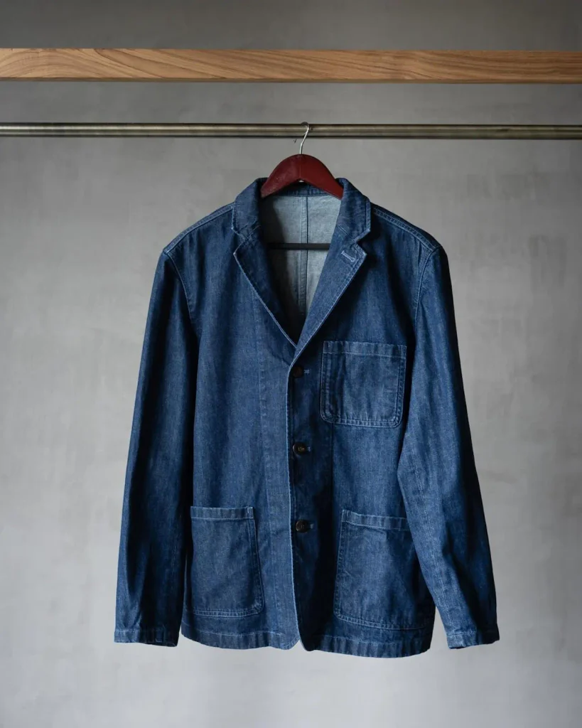 Close-up of a jacket hanging on a wooden hanger, showing its shoulder construction and upper-body proportions.