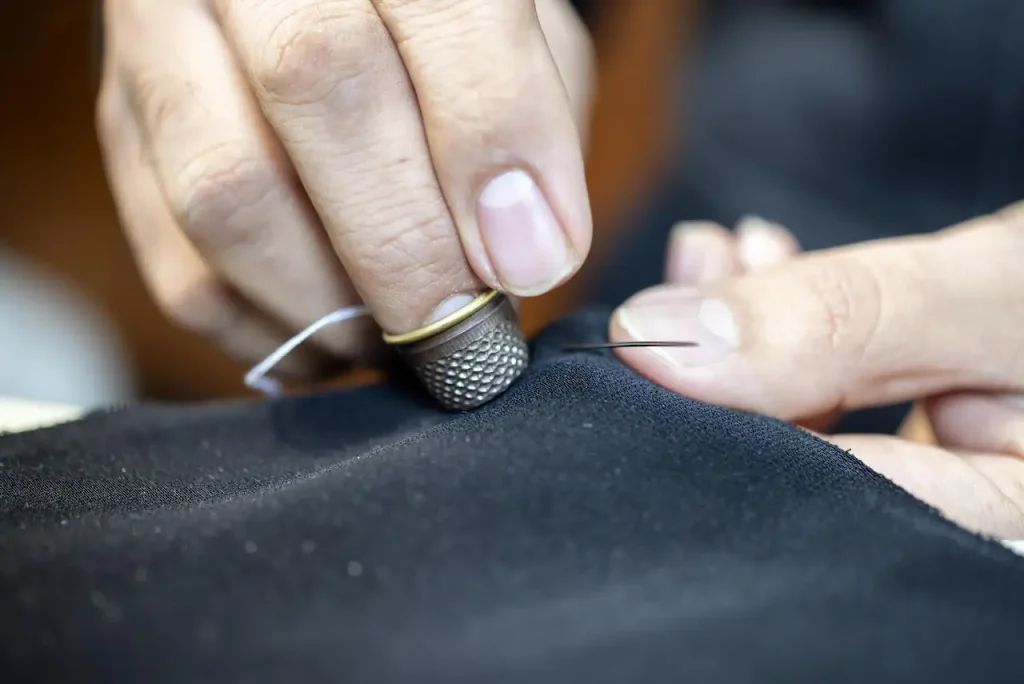 Close-up of a garment being stitched by hand with needle and thread